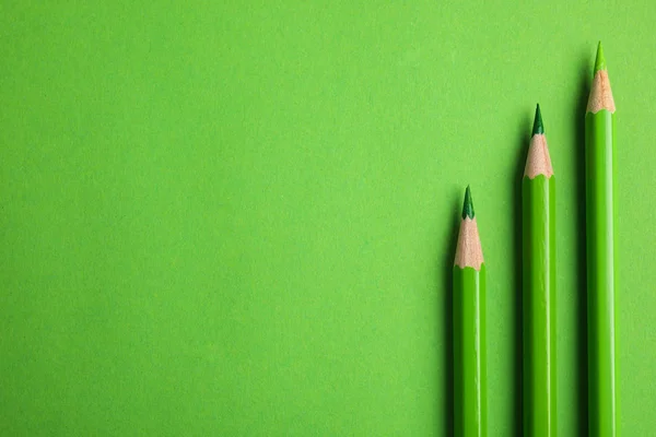 Composição de leigos planos com lápis de cor no fundo verde. Espaço para texto — Fotografia de Stock