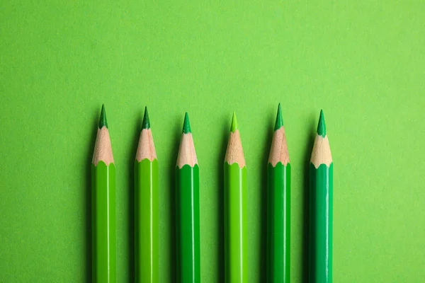 Platt låg sammansättning med färg pennor på grön bakgrund — Stockfoto