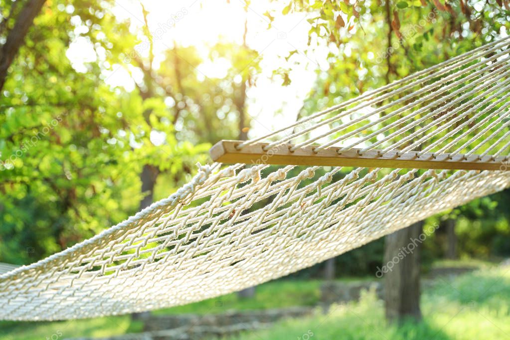 Comfortable net hammock hanging in green garden, closeup