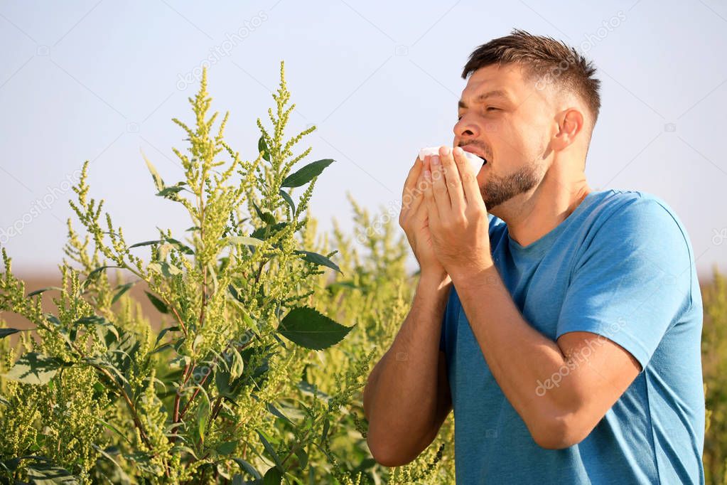 Man suffering from ragweed allergy outdoors on sunny day