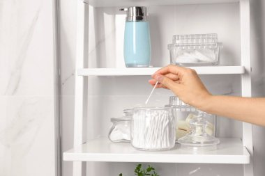 Kapalı alandaki kavanozdan pamuk çubuğu alan genç bir kadın.