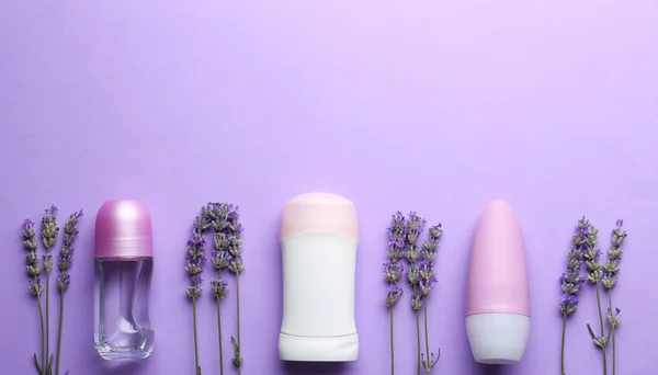 Deodoranti femminili e fiori di lavanda su sfondo lilla, posa piatta — Foto Stock