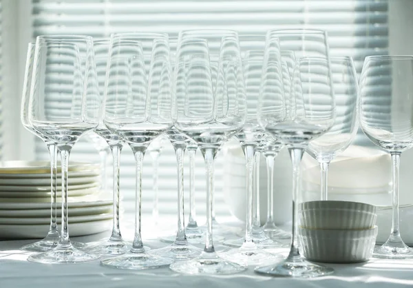 Conjunto de copos de vinho vazios e louça na mesa dentro de casa — Fotografia de Stock