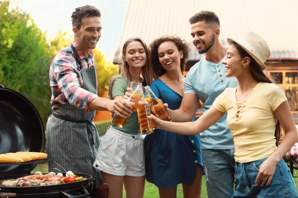 Gruppo di amici con bevande vicino barbecue all'aperto — Foto Stock