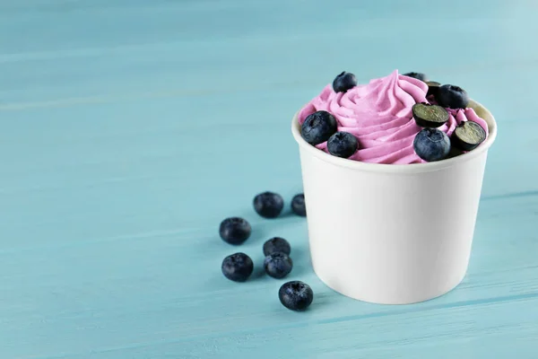 Copa con sabroso yogur helado y arándanos en la mesa de madera azul. Espacio para texto — Foto de Stock