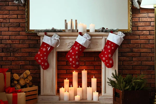 Chimenea decorativa con medias de Navidad y regalos en el interior de la habitación con estilo —  Fotos de Stock