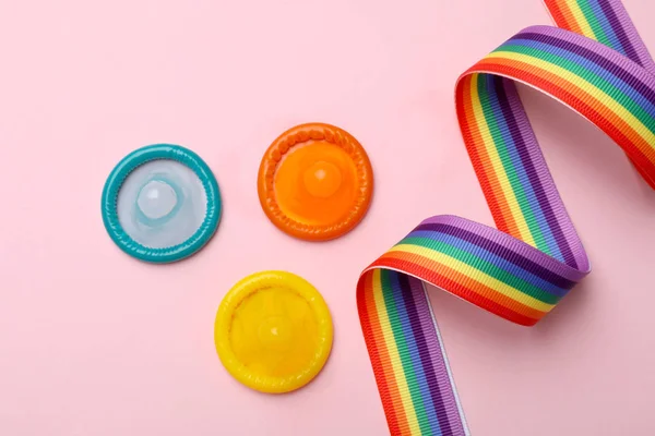 Composición plana con condones de colores y cinta de arco iris sobre fondo rosa. Concepto LGBT —  Fotos de Stock