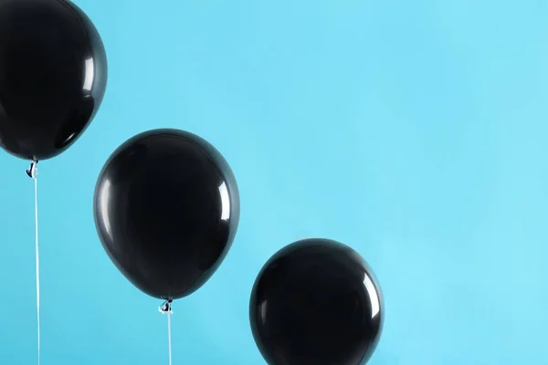 Black balloons on blue background, space for text. Halloween party
