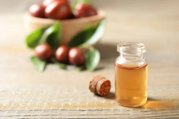 Garrafa de vidro com óleo de jojoba na mesa de madeira. Espaço para texto — Fotografia de Stock