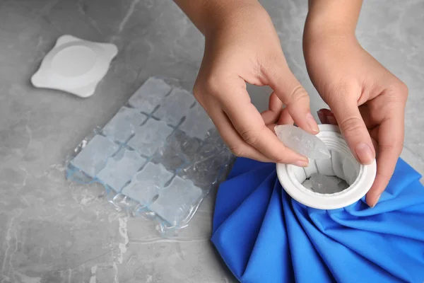 Egy nő jégkockákat tesz a csomagba a márványasztalnál, közelkép — Stock Fotó
