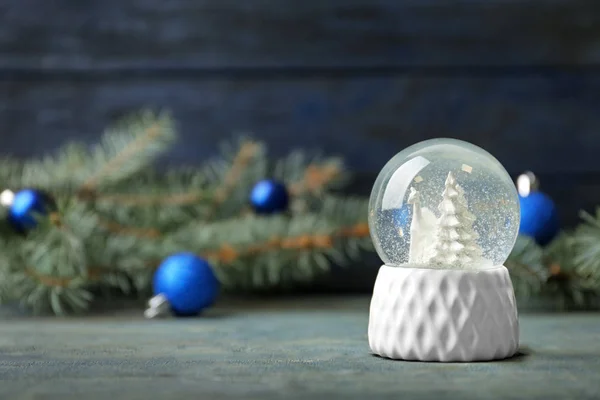 Sněhová koule s jeleny a stromy na modrém dřevěném stole, prostor pro text. Vánoční sezóna — Stock fotografie