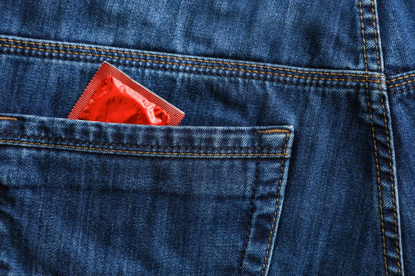 Closeup view of jeans with condom in pocket. Safe sex concept