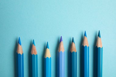 Açık mavi arkaplanda renkli kalemlerle düz konum