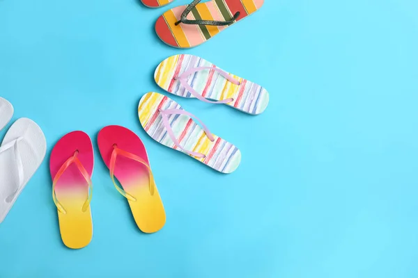 Composición plana con diferentes chanclas sobre fondo azul, espacio para texto. Accesorios de playa de verano — Foto de Stock