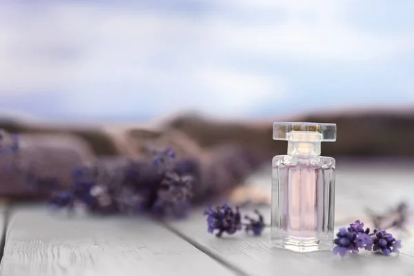 Flaska lyx parfym och lavendel blommor på vitt träbord utomhus. Utrymme för text — Stockfoto