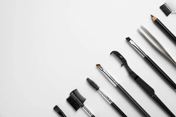 Set of professional eyebrow tools on white background, flat lay. Space for text