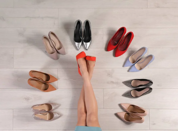 Женщина и различные стильные туфли на деревянном полу, вид сверху — стоковое фото