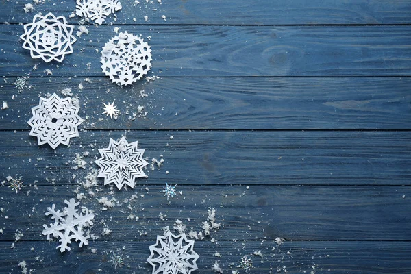 Composición plana con copos de nieve de papel sobre fondo azul de madera, espacio para el texto. Temporada de invierno — Foto de Stock