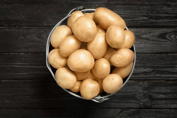 Raw fresh organic potatoes on black wooden background, top view — Stock Photo, Image