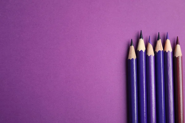 Плоска композиція з кольоровими олівцями на фіолетовому фоні. Простір для тексту — стокове фото