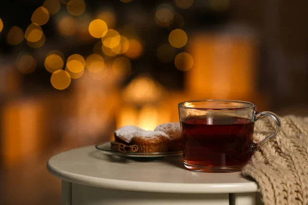 Xícara de chá quente na mesa branca contra luzes turvas, espaço para texto. Inverno acolhedor — Fotografia de Stock