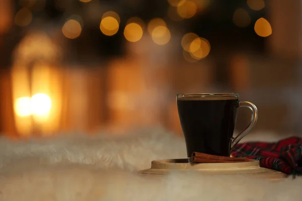 Xícara de café em pele branca contra luzes embaçadas, espaço para texto. Inverno acolhedor — Fotografia de Stock