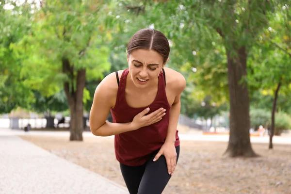 Young woman having heart attack while running in park