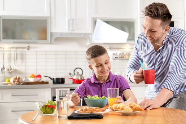 Dad and son having breakfast together in kitchen