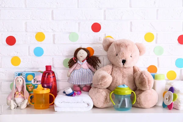 Accesorios para bebés en estante cerca de la pared de ladrillo blanco —  Fotos de Stock