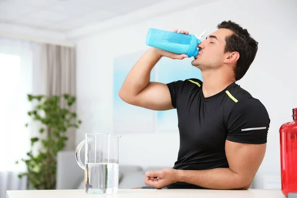 Jovem atlético bebendo batido de proteína em casa, espaço para texto — Fotografia de Stock