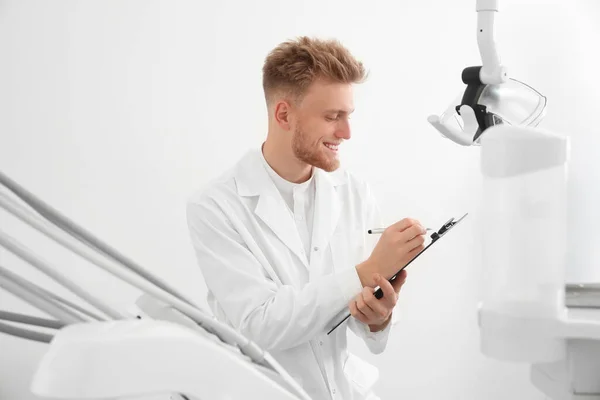 Odontólogo masculino profesional con portapapeles en clínica — Foto de Stock