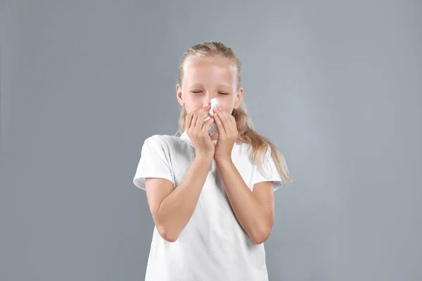 Bambina che soffre di allergia su sfondo grigio — Foto Stock