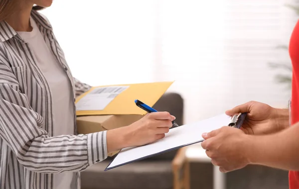 Mujer firmando por paquetes entregados en casa, primer plano. Servicio de mensajería — Foto de Stock