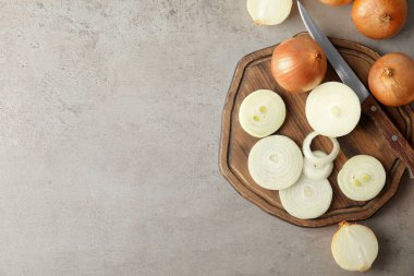 Gri masa üzerinde kesik ve tüm soğan ile düz kompozisyon, metin için boşluk