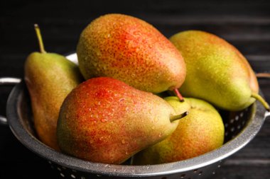 Olgun sulu armutları olan Colander karanlık masada, yakın plan