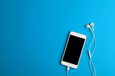 Mavi arka planda kulaklığı olan modern bir telefon. Metin için boşluk