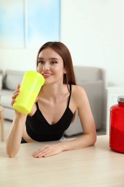 Genç kadın kapalı masada protein shake içme