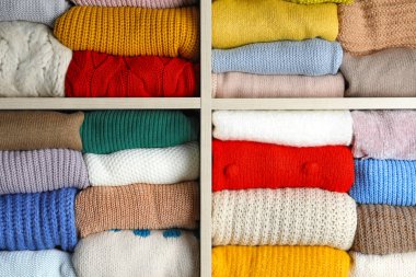 Arkaplan olarak katlanmış renkli kış kazakları raflarda