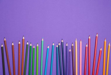 Mor arka plan üzerinde renkli kalemler, düz yatıyordu. Metin için alan