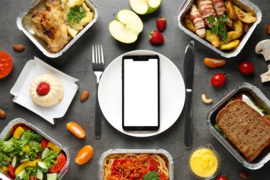 Beslenme çantaları ve akıllı telefonlu düz kompozisyon gri masanın üzerinde, tasarım için model. Sağlıklı yemek servisi.