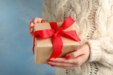 Mavi arka plan üzerinde Noel hediyesi tutan genç kadın, closeup