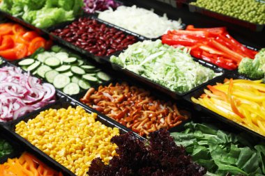 Arka planda farklı taze malzemeler bulunan salata barı.