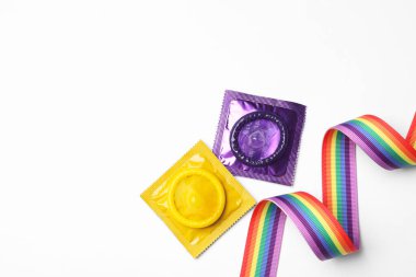 Renkli prezervatifler ve beyaz arka planda gökkuşağı kurdelesi, üst manzara. Lgbt kavramı