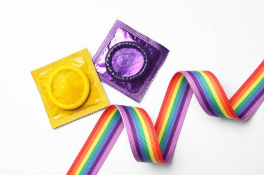Renkli prezervatifler ve beyaz arka planda gökkuşağı kurdelesi, üst manzara. Lgbt kavramı