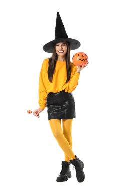 Cadılar Bayramı partisi için beyaz arka planda Jack O 'Lantern şeker kabı ile cadı kostümü giyen güzel bir kadın.