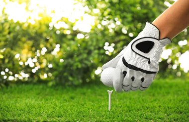 Oyuncu yeşil sahada golf topuna vuruyor, yakın plan.