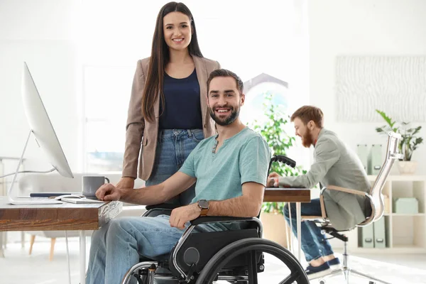 Junger Mann im Rollstuhl mit Kollegen am Arbeitsplatz — Stockfoto