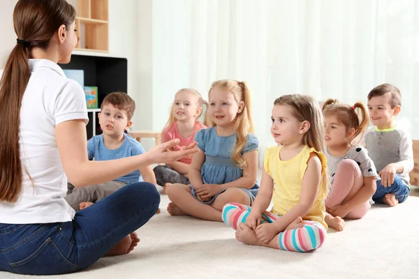 Kleuterleidster en kleine kinderen binnenshuis. Leren en spelen — Stockfoto