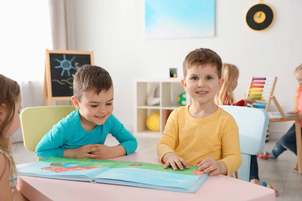 Carino i bambini che leggono il libro insieme a tavola all'interno. Imparare e giocare — Foto Stock