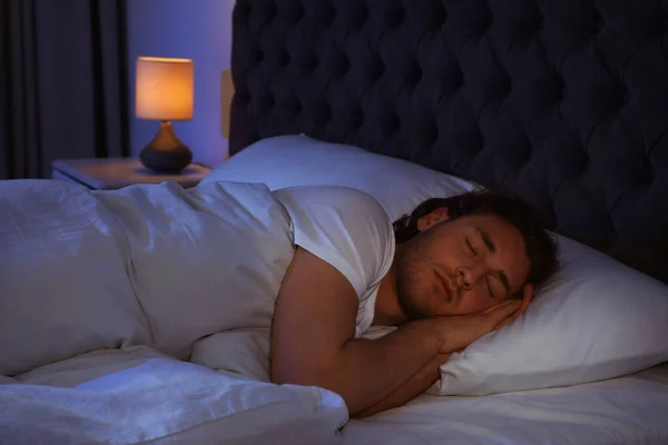 Beau jeune homme dormant sur un oreiller la nuit. Au lit. — Photo